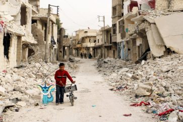 A Syrian boy walks with his bicycle in the devastated Sukari district in the northern city of Aleppo on November 13, 2014, BARAA AL-HALABI/AFP/Getty Images)