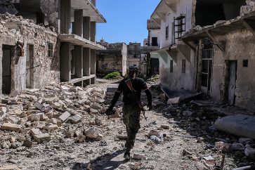 Militant walks between destructed structures in eastern Aleppo