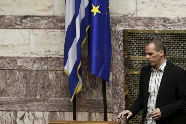 Greek Finance Minister Yanis Varoufakis walks next to a European Union and a Greek national flag during a parliamentary session in Athens April 2, 2015. Greece sent an updated list of reforms to lenders on Wednesday to try to unlock financial aid and avoid a default but euro zone officials said more work was needed before new funds could be released.  REUTERS/Alkis Konstantinidis