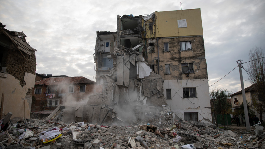 Dust rises from falling parts of a destroyed building during an aftershock in Thumane, western Albania, Wednesday, Nov. 27, 2019.  A deadly earthquake struck in the coastal cities of Albania, early Tuesday, killing at least 27 people and injuring more than 650. (AP Photo/Petros Giannakouris)