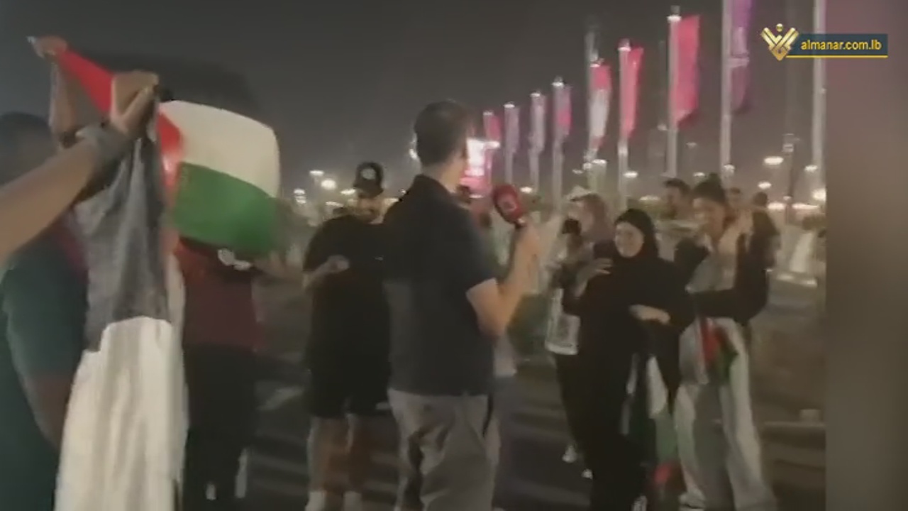 Arab fans raising Palestine's flag behind Israeli correspondent in rejection of his presence