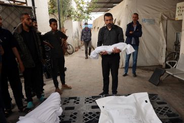A man carries the shrouded body of a child killed in overnight Israeli bombardment, in the front of the morgue of a hospital in Rafah in the southern Gaza Strip on April 27, 2024, as the conflict between Israel and the militant group Hamas continues. (Photo by AFP)