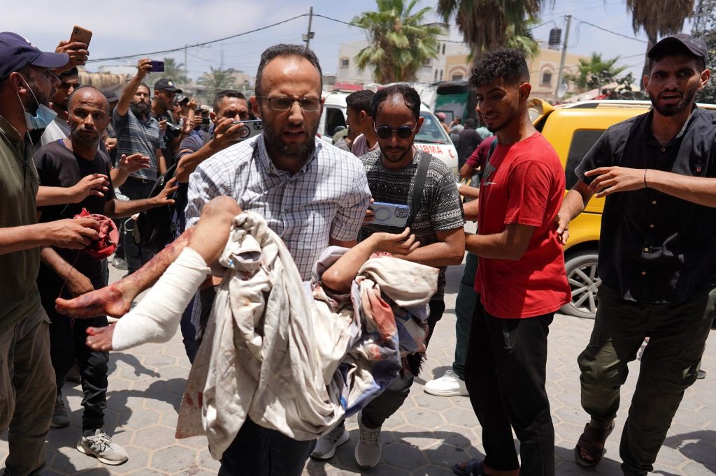 EDITORS NOTE: Graphic content / A man rushes carrying an injured child following the Israeli bombardment of a residential apartment in Deir al-Balah and of al-Maghazi, as he arrives at the al-Aqsa Martyrs Hospital in Deir al-Balah, in the central Gaza Strip, on June 8, 2024, amid the ongoing conflict between Israel and the Palestinian militant group Hamas. (Photo by Bashar TALEB / AFP)