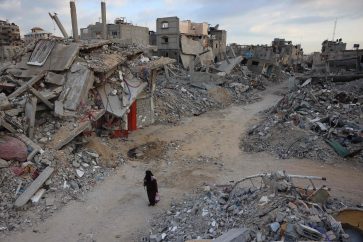 A woman walks past destroyed buildings in Khan Yunis in the southern Gaza Strip on October 17, 2024, amid the ongoing war between Israel and the Palestinian militant group Hamas in the besieged Palestinian territory. (Photo by BASHAR TALEB / AFP)