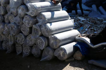 A boy sits as Palestinians gather to receive aid provided by UNRWA including food supplies